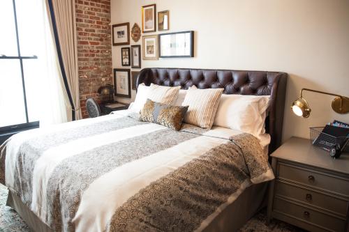 Cozy bedroom featuring a tufted headboard, decorative pillows, and framed art on the wall.