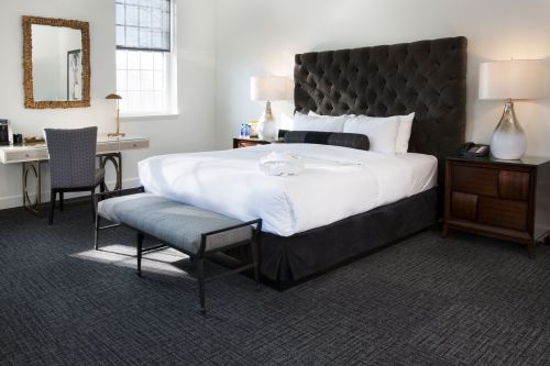 A modern hotel room featuring a large bed, stylish decor, a desk, and soft lighting.