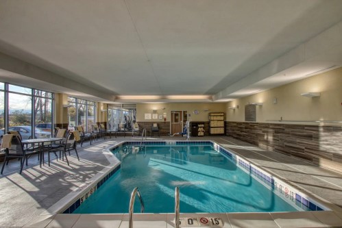 Indoor swimming pool area with lounge chairs, large windows, and a clean, modern design.