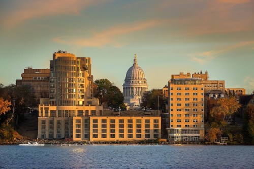 Cityscape of Madison, Wisconsin, featuring modern buildings and the iconic state capitol dome at sunset.