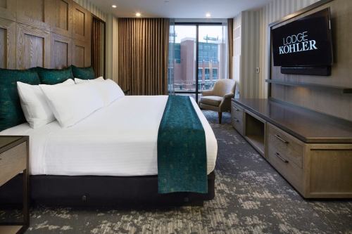 Modern hotel room featuring a king-sized bed, stylish decor, and a large window with a view.
