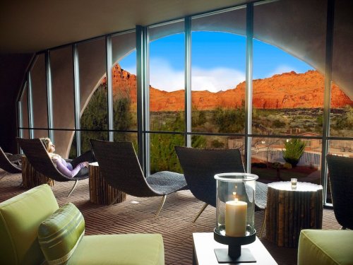 A serene lounge area with modern chairs, featuring large windows showcasing a stunning red rock landscape outside.