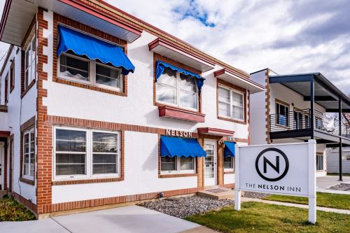 Exterior view of The Nelson Inn, featuring blue awnings, a sign, and a landscaped entrance.