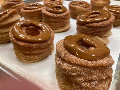 A tray of freshly baked pastries with a cinnamon sugar coating and topped with a smooth chocolate glaze.