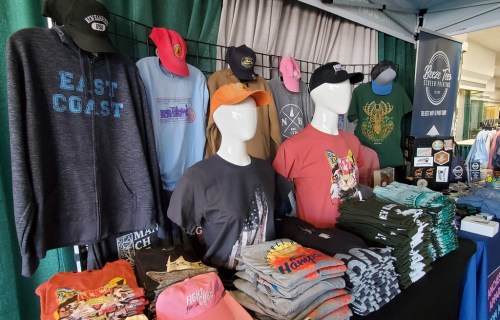 A display of various t-shirts and hats on mannequins and tables at a market stall.