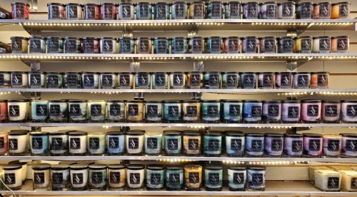 A wall display of colorful candles arranged in rows, featuring various designs and labels.