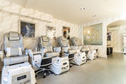 A modern nail salon featuring several pedicure chairs in a bright, stylish interior with decorative wall art.