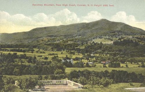 View of Ascutney Mountain from High Court, with lush green fields and a distant village in the foreground.