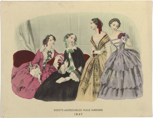 Four elegantly dressed women in 19th-century fashion, showcasing colorful gowns and hairstyles, posed together.