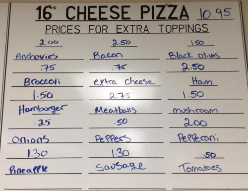 Menu board displaying prices for a 16" cheese pizza and extra toppings, including various meats and vegetables.