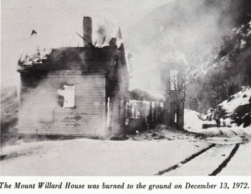 Black and white photo of the Mount Willard House, burned down on December 13, 1972, with smoke rising from the ruins.