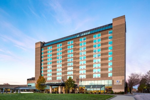 Modern hotel building with large windows, set against a clear sky and landscaped grounds.
