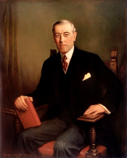 Portrait of a man in a suit, seated with a book in hand, exuding a dignified and formal demeanor.