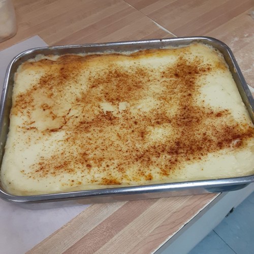 A rectangular baking dish filled with creamy mashed potatoes, topped with a sprinkle of paprika.