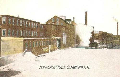 Historic image of Monadnock Mills in Claremont, NH, featuring brick buildings and smoke rising from chimneys.