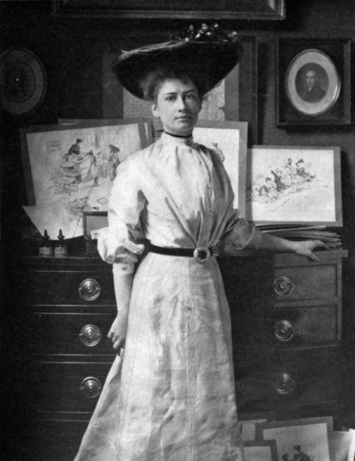 A woman in a vintage dress and large hat stands beside a dresser, surrounded by artwork and photographs.