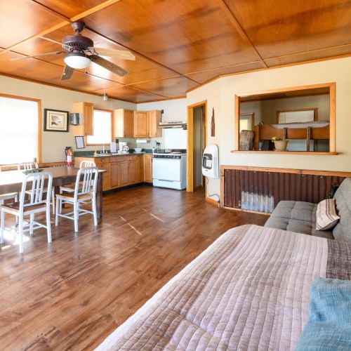 Cozy interior of a kitchen and living area with wooden ceiling, dining table, and comfortable seating.