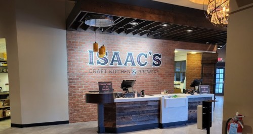 Interior of Isaac's Craft Kitchen & Brewery featuring a brick wall, counter, and modern decor.