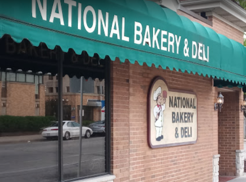 Sign for "National Bakery & Deli" on a brick building with a green awning.