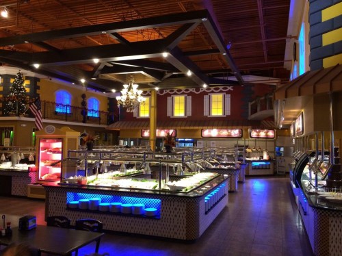 A spacious buffet restaurant with colorful decor, featuring multiple food stations and bright lighting.