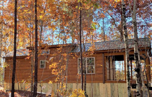 A cozy wooden cabin surrounded by vibrant autumn foliage and trees.