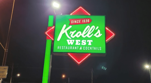 Neon sign for Kroll's West Restaurant & Cocktails, established in 1936, illuminated at night.