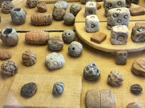 A collection of ancient stones and artifacts displayed on a textured surface, featuring various shapes and patterns.