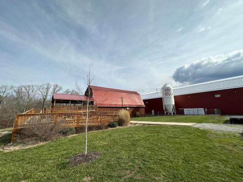 A red barn with a metal roof, surrounded by green grass and trees, next to a white water tower.