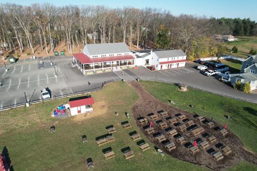 Aerial view of a building with a red roof, surrounded by a parking lot and outdoor seating area with picnic tables.