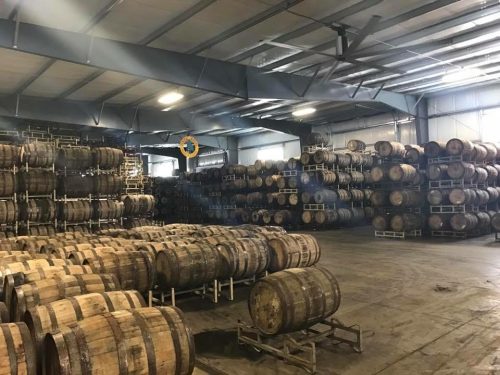A spacious warehouse filled with stacked wooden barrels, arranged neatly on racks.