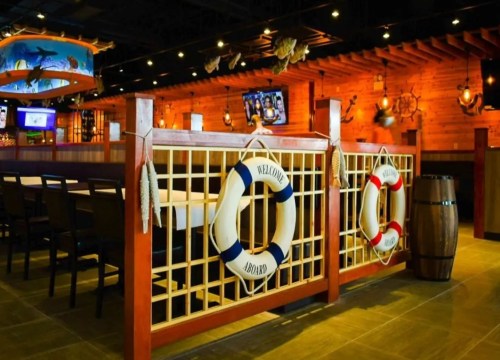 Interior of a nautical-themed restaurant featuring life rings, wooden decor, and a cozy dining area.