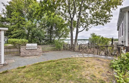 A serene outdoor space with a grill, surrounded by trees and a view of a calm waterway in the background.