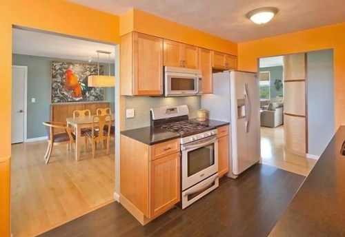 Bright kitchen with wooden cabinets, stainless steel appliances, and an open layout leading to a dining area.