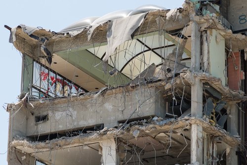 A close-up of a partially demolished building, showing exposed floors and structural damage.