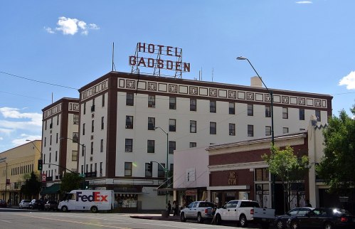 Historic Hotel Gadsden building with a prominent sign, surrounded by shops and clear blue sky.