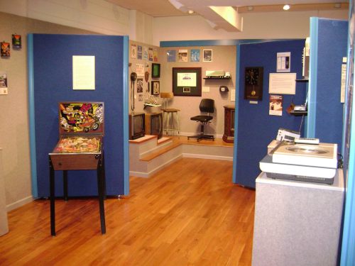 A room with blue walls showcasing vintage items, including a pinball machine and various retro decor.