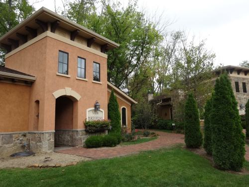 A charming building with orange stucco and stone accents, surrounded by greenery and landscaped pathways.