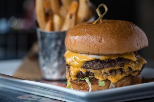 A juicy cheeseburger with two patties, melted cheese, and lettuce, served with a side of crispy fries.