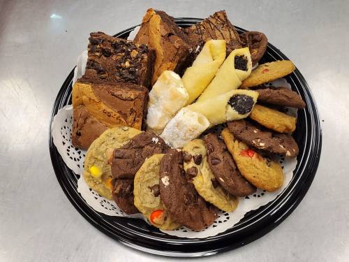 A platter of assorted baked goods, including brownies, cookies, and pastries, arranged on a decorative tray.