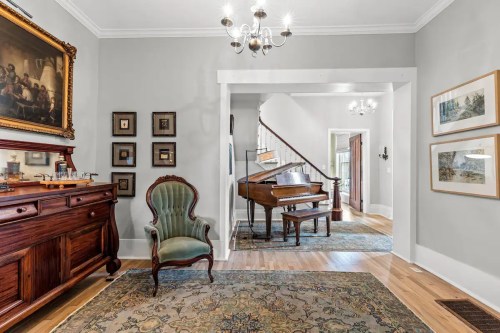 A cozy entryway featuring a vintage chair, a grand piano, and framed artwork on light gray walls.