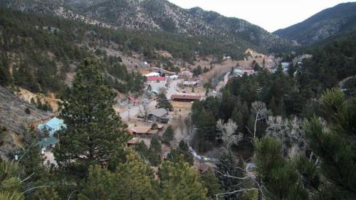 Aerial view of a small town nestled in a mountainous landscape, surrounded by trees and hills.