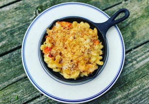 A cast-iron skillet filled with baked macaroni and cheese, topped with a golden, crispy layer, on a white plate.