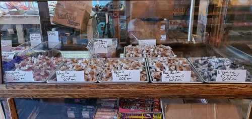 A display case filled with various types of caramels, labeled with flavors like cinnamon, vanilla, and licorice.