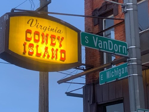 A vintage sign for Virginia Coney Island next to street signs for S Van Dorn and E Michigan.