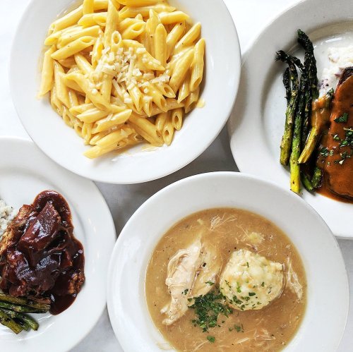 A top-down view of four bowls featuring pasta, chicken and dumplings, beef, and asparagus.