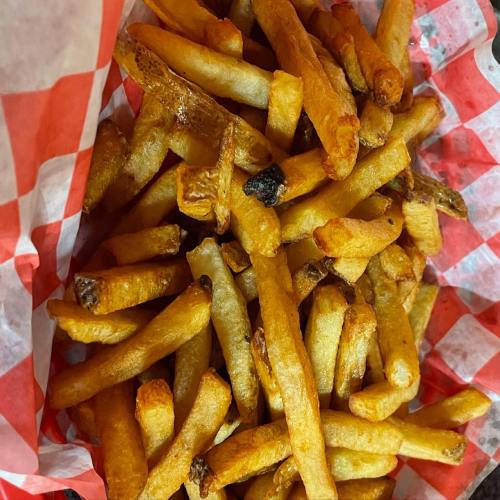 A close-up of golden-brown French fries in a red and white checkered paper basket.