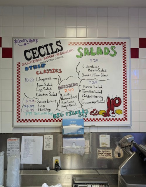Menu board at Cecil's Deli featuring daily specials, salads, and classic dishes with prices listed.