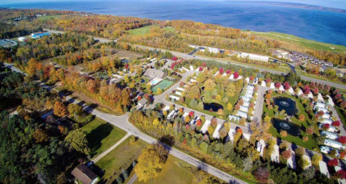 Aerial view of a colorful autumn landscape with a lake, trees, and a residential area near the coast.