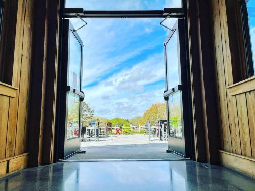 View from an open doorway, showcasing a bright sky and outdoor seating area surrounded by greenery.
