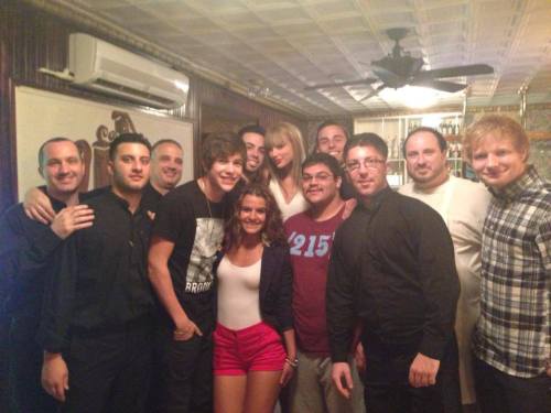 A group of people posing together in a restaurant, smiling and dressed casually.